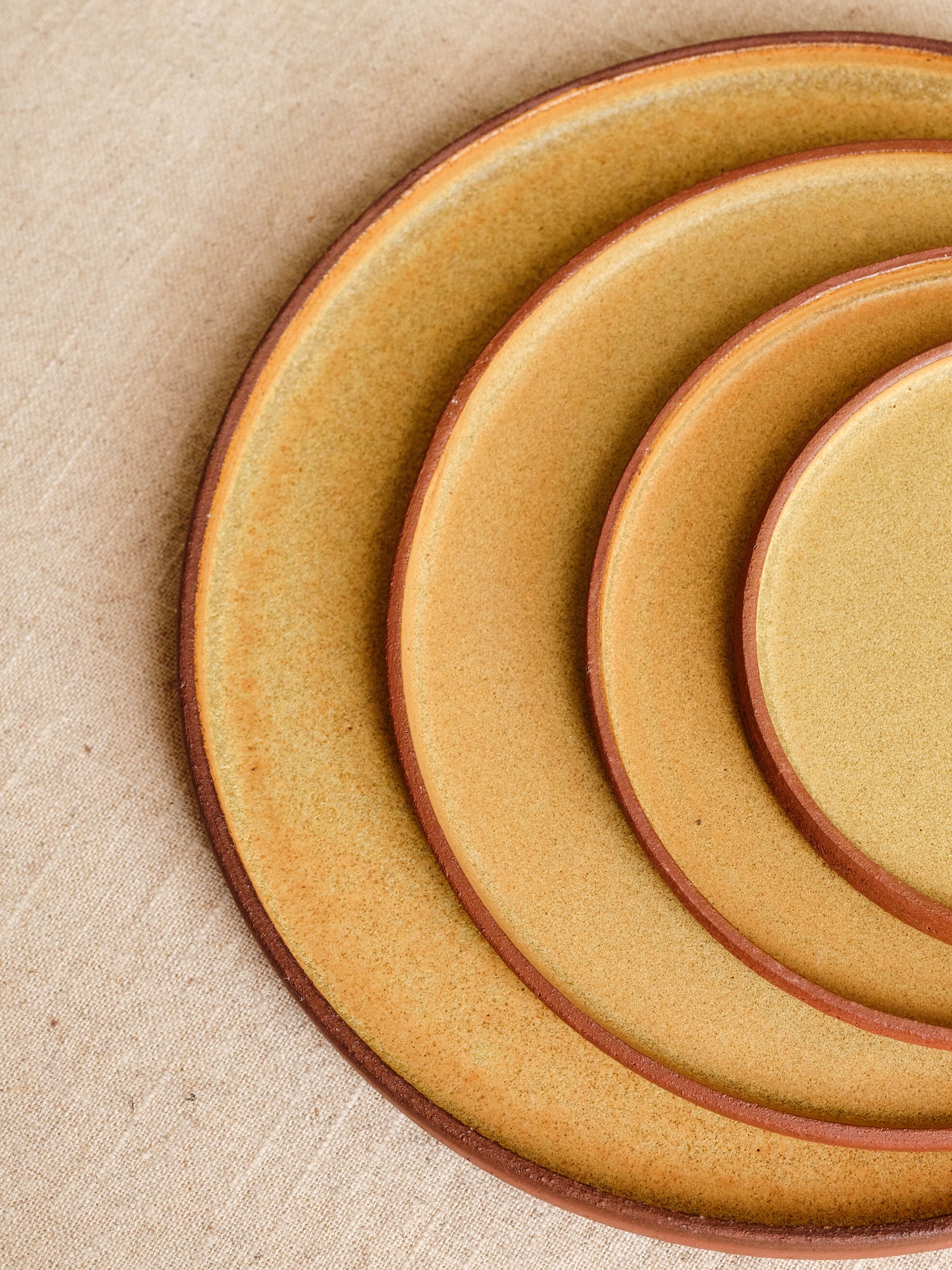 Set of ceramic plates with a brown rim on a beige fabric background