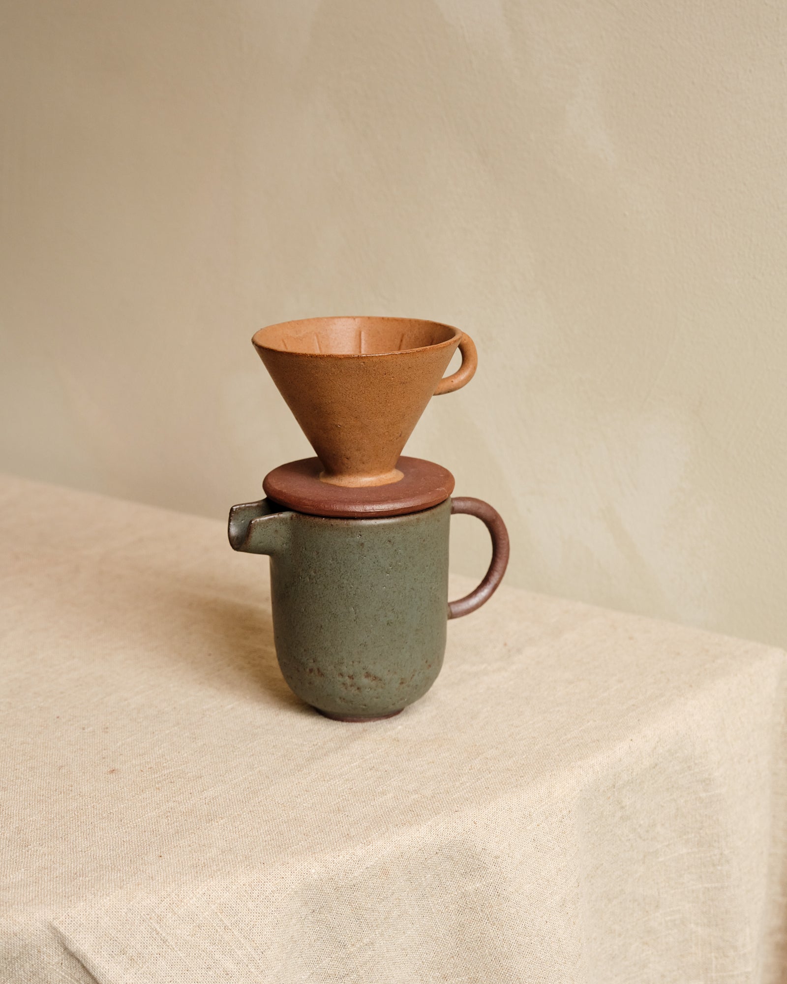 Ceramic coffee maker with ceramic filter on a beige surface