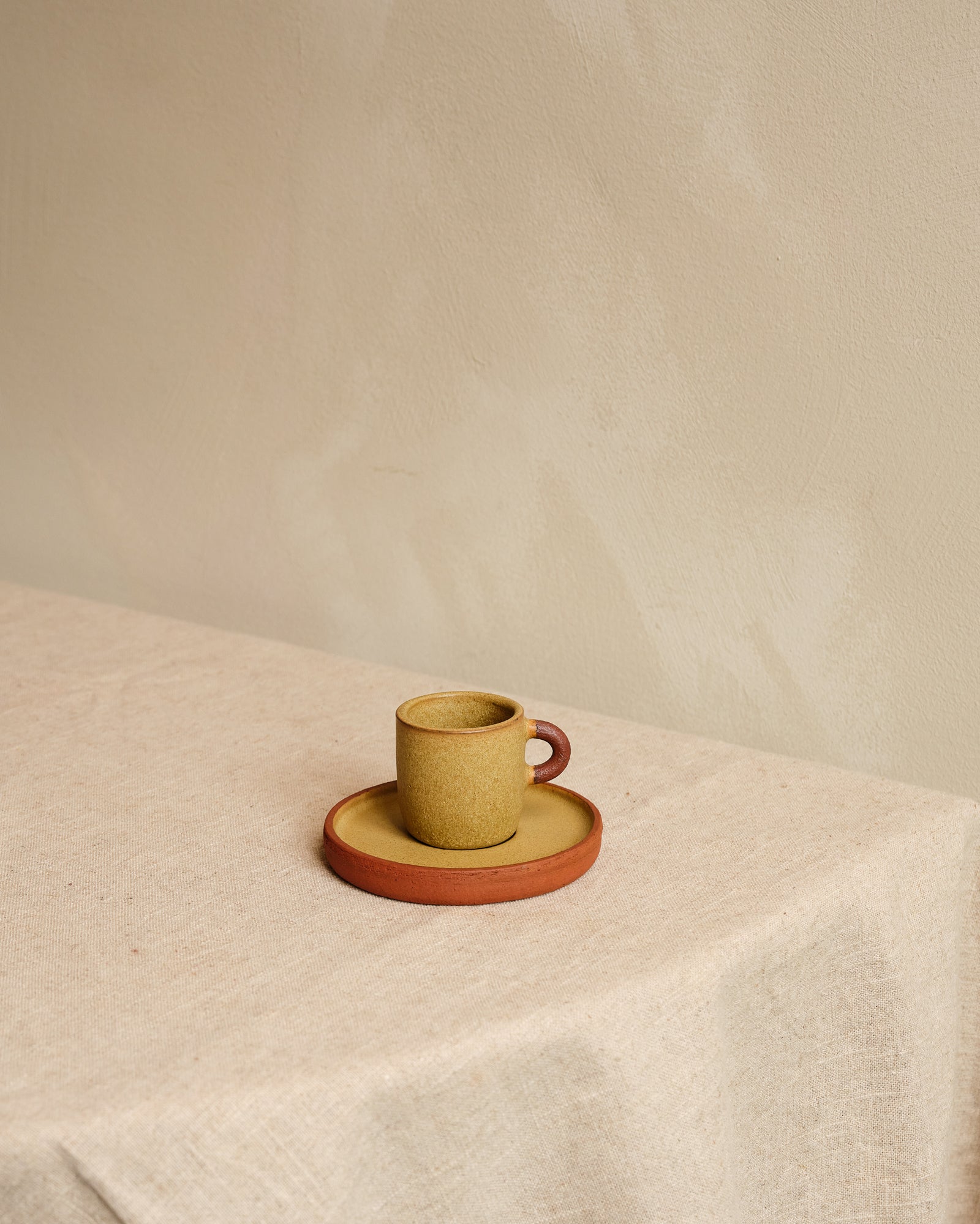 Ceramic cup and saucer set on a textured surface with a neutral background