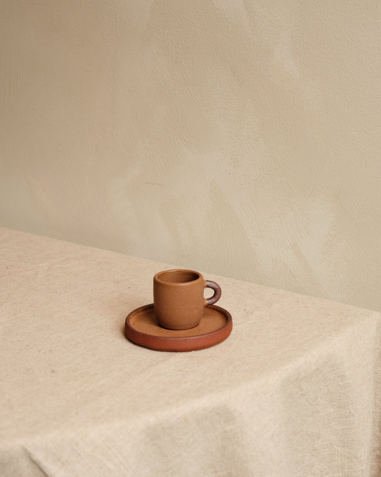 Ceramic cup and saucer set on a textured surface with a neutral background