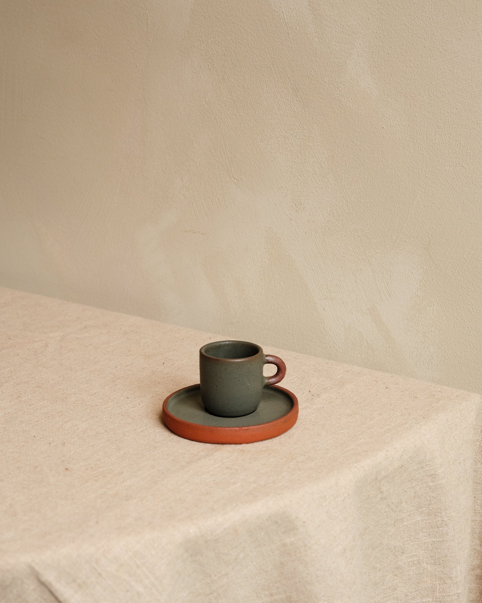 Ceramic cup and saucer set on a textured surface with a neutral background