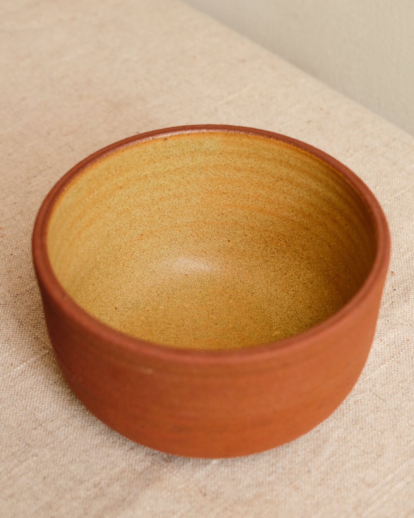 Terracotta bowl on a beige fabric background