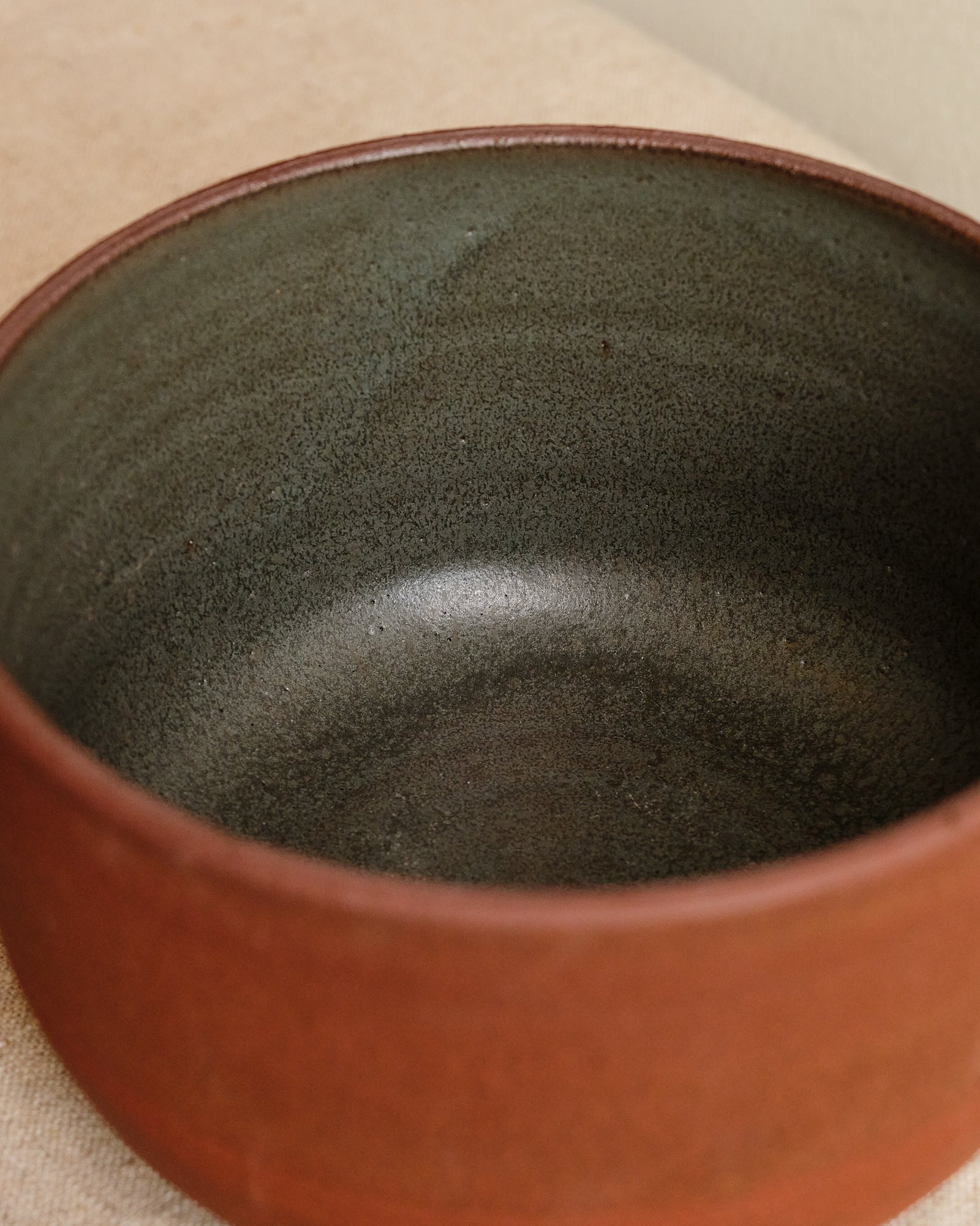 Close-up of a ceramic bowl with a brown rim and greenish interior.