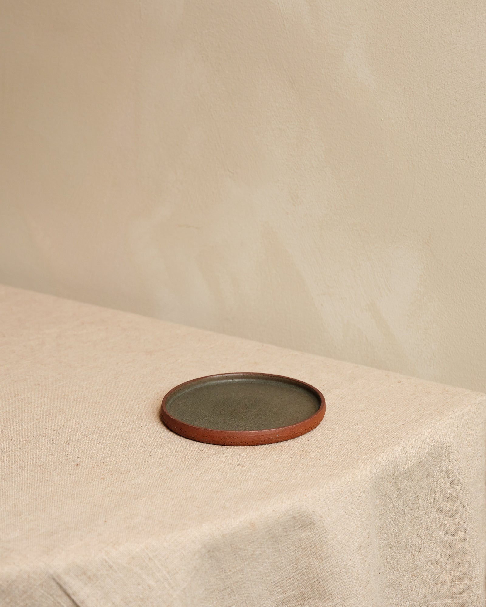 Ceramic plate on a textured beige surface with a plain background