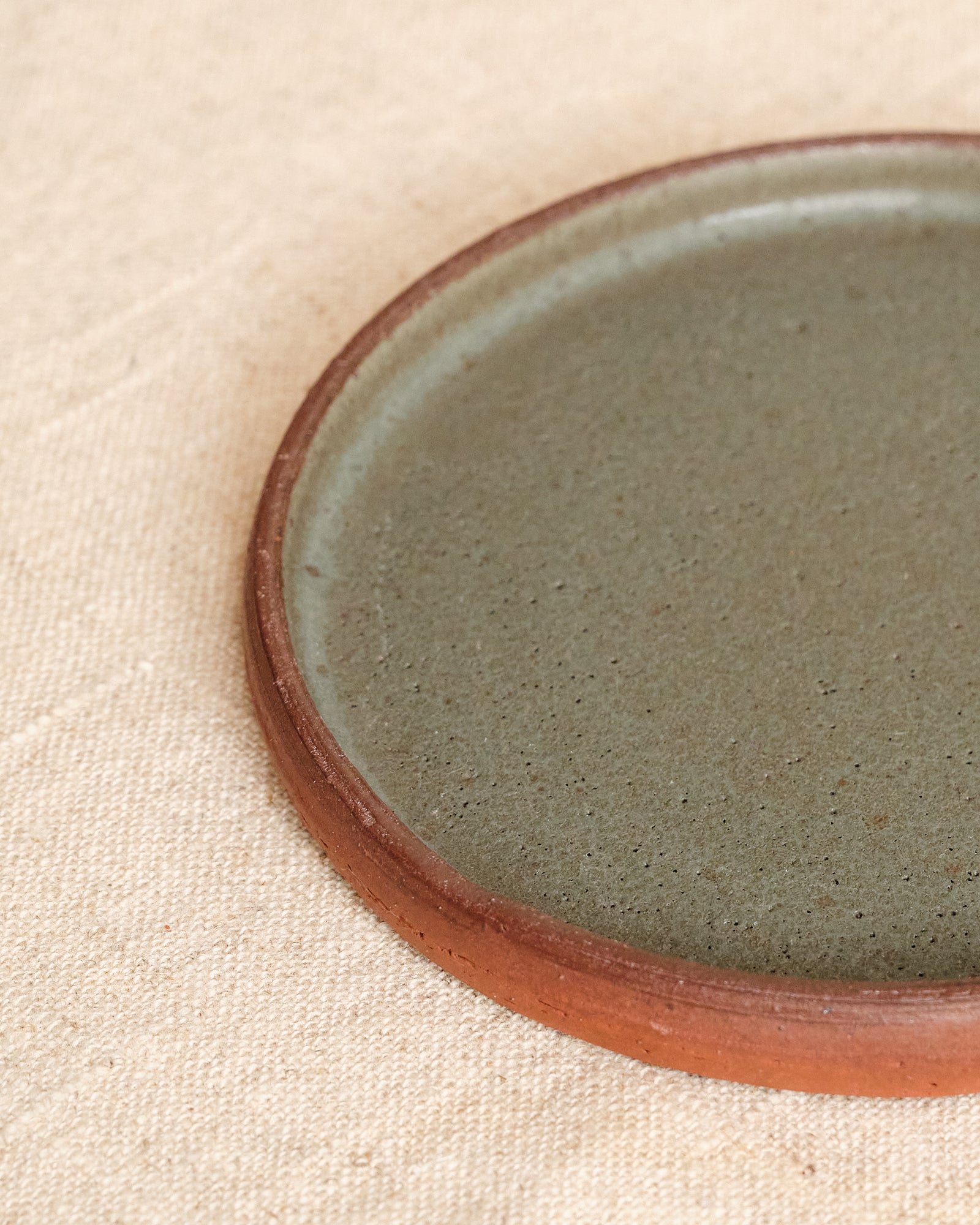 Ceramic plate with a brown rim on a beige fabric background
