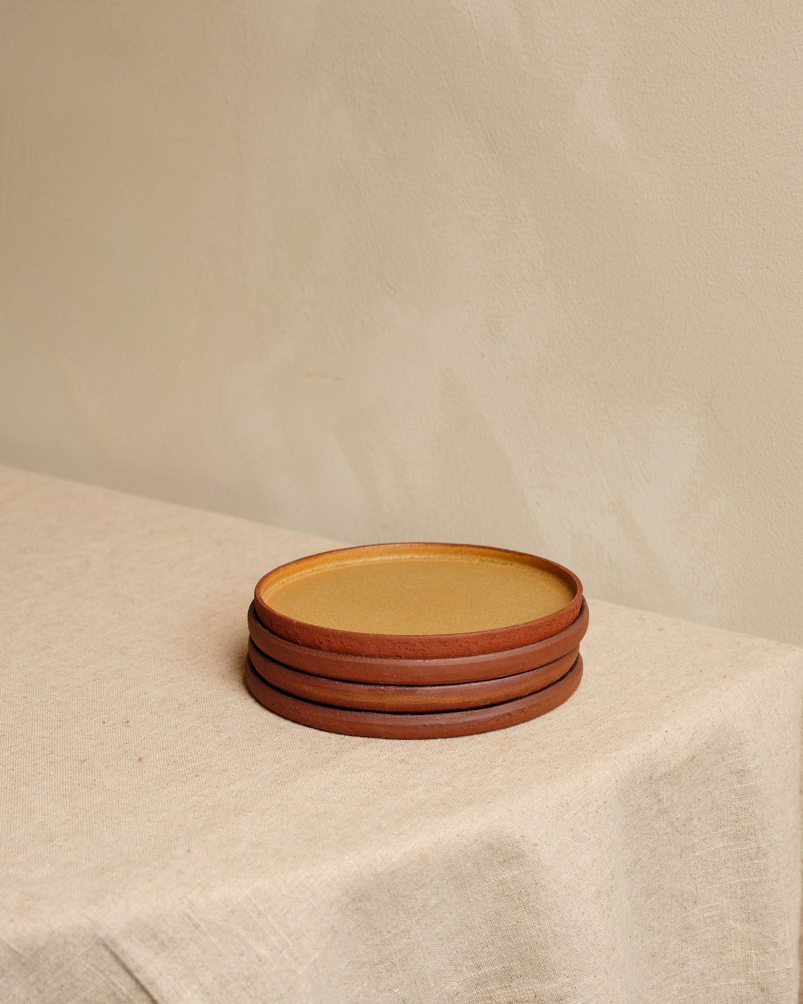 Stack of ceramic plates with a brown rim on a beige surface