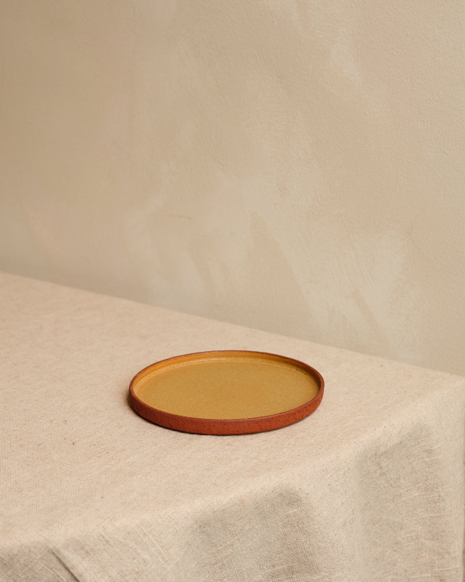 Round ceramic plate with brown rim on a beige surface