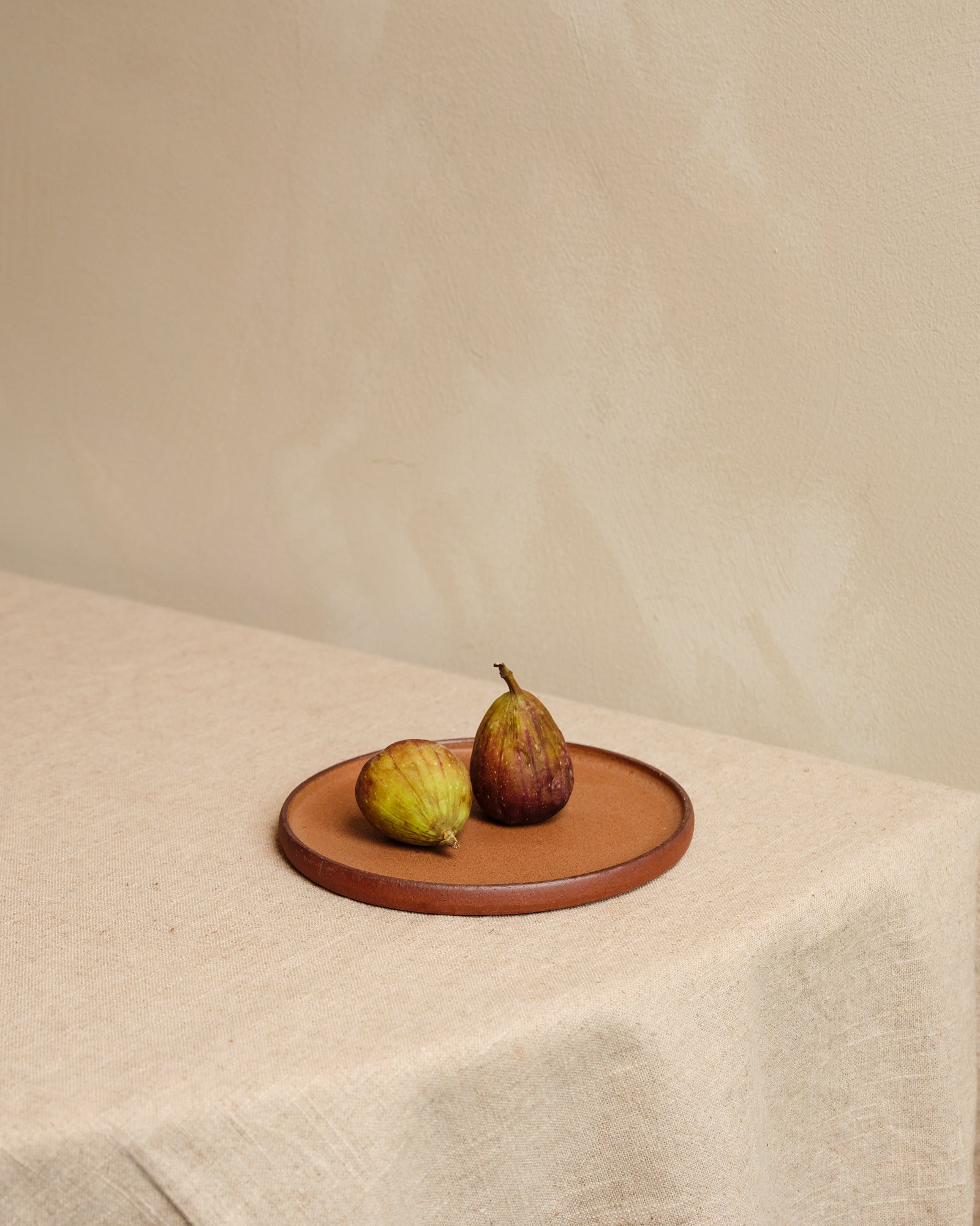 Two figs on a ceramic plate with a plain background