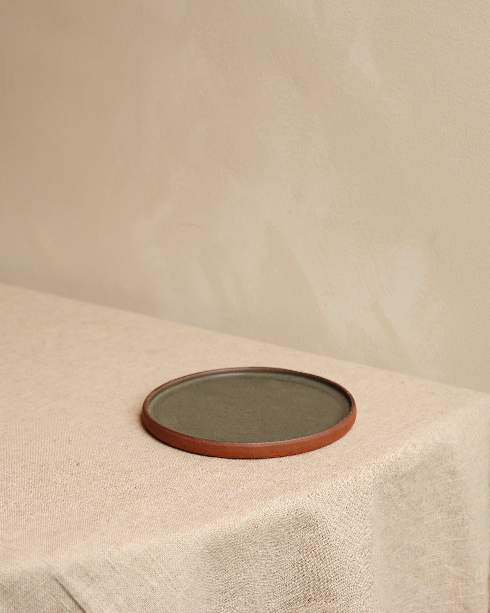 Round ceramic plate with brown rim on a beige surface