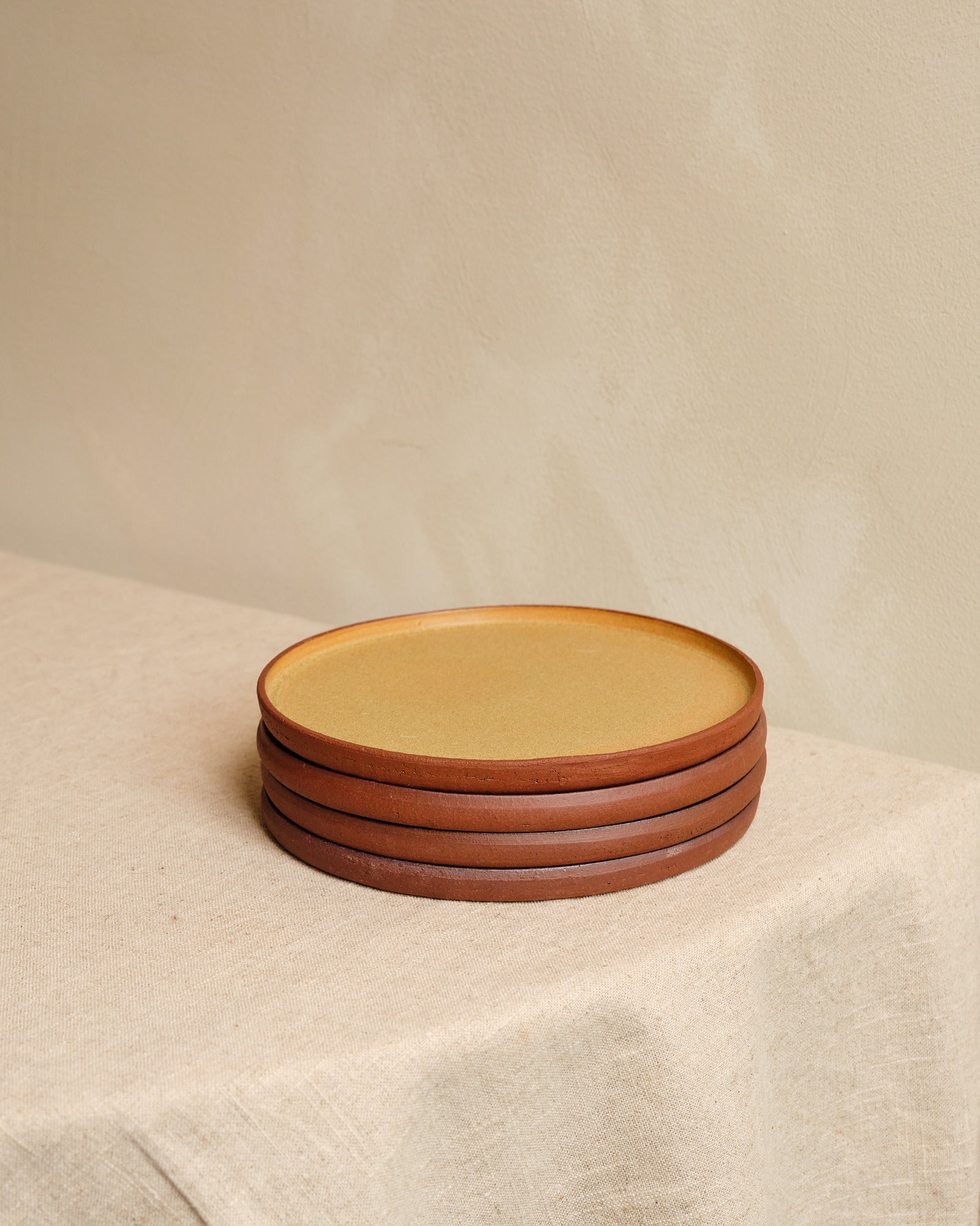 Stack of ceramic plates on a beige surface with a neutral background