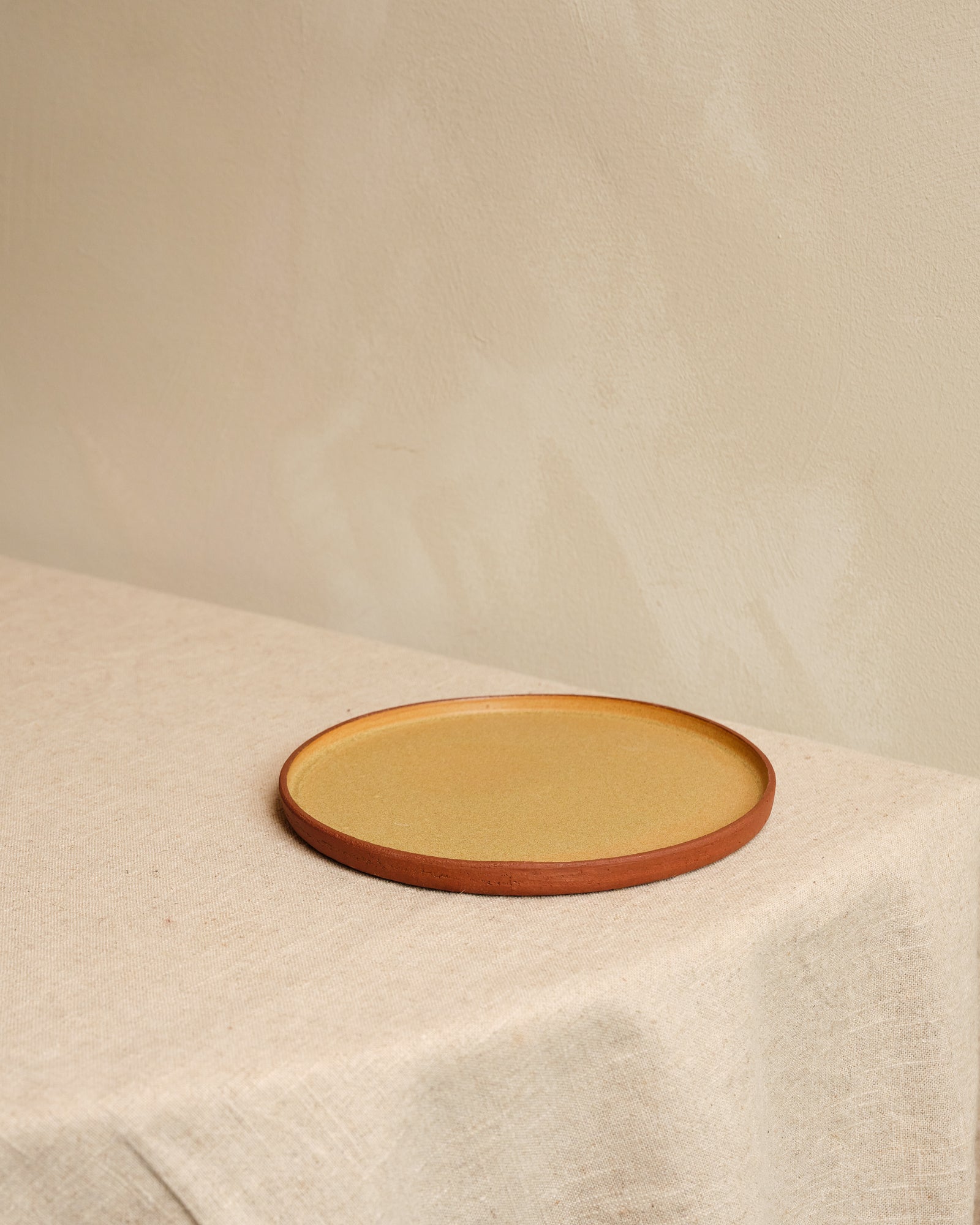 Round ceramic plate with a brown rim on a beige surface