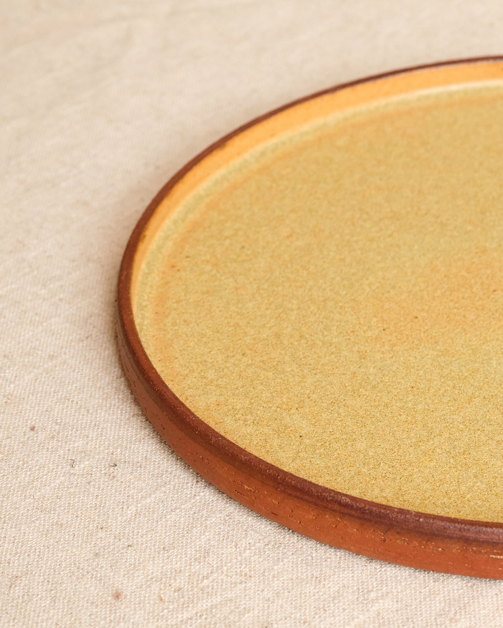 Close-up of a ceramic plate with a wooden rim on a beige fabric background
