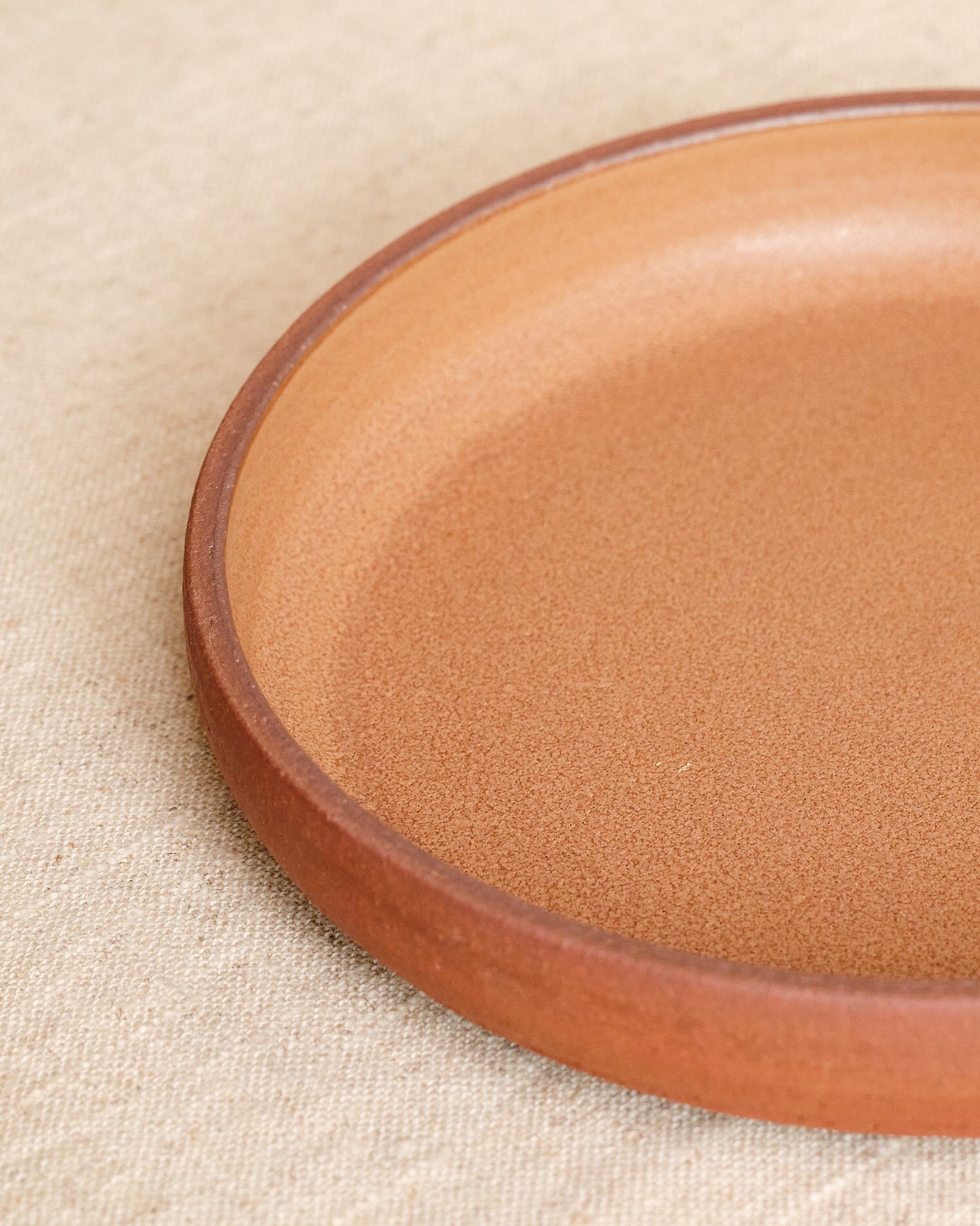 Close-up of a brown ceramic plate on a beige fabric background