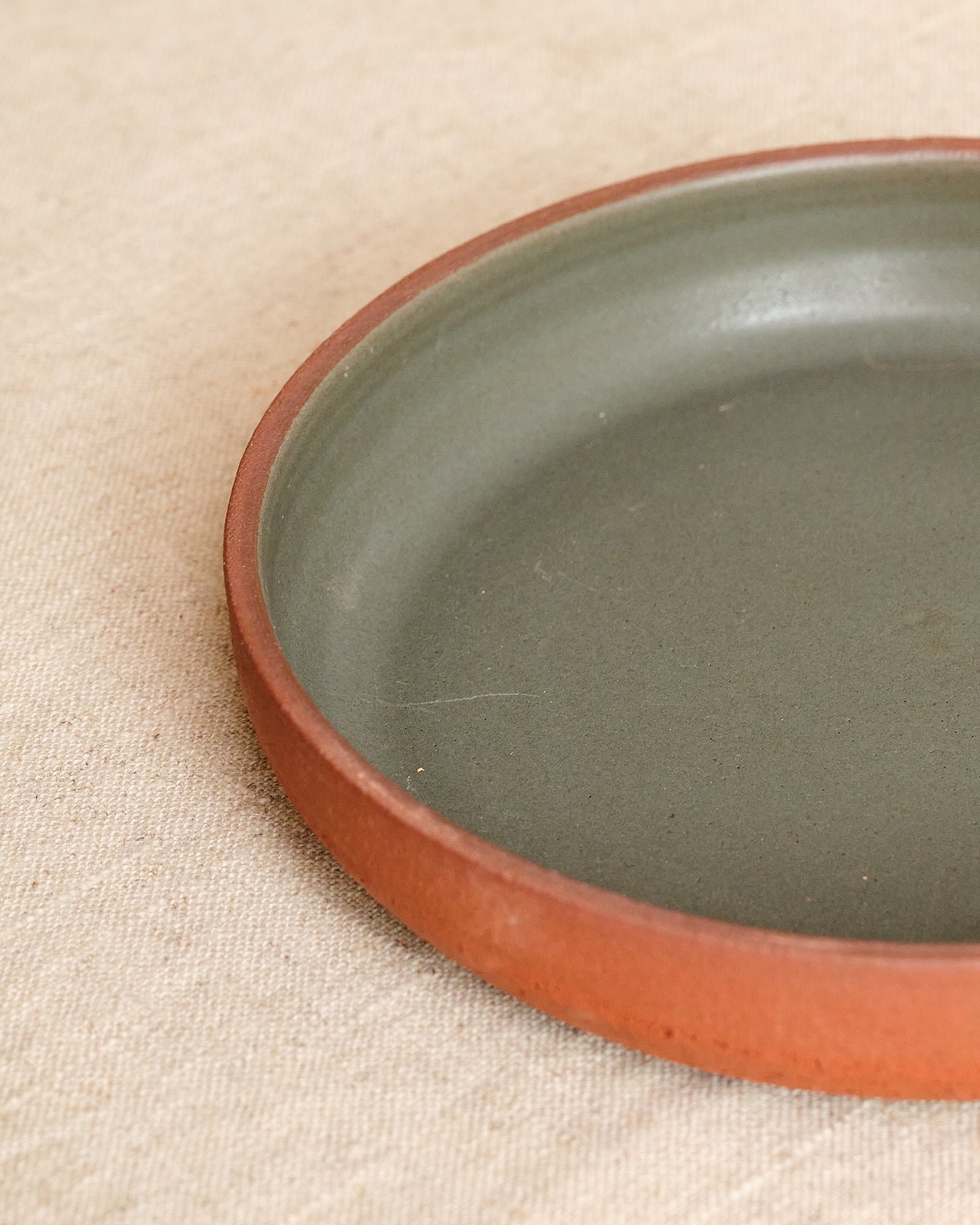 Ceramic plate with a brown rim on a beige fabric background