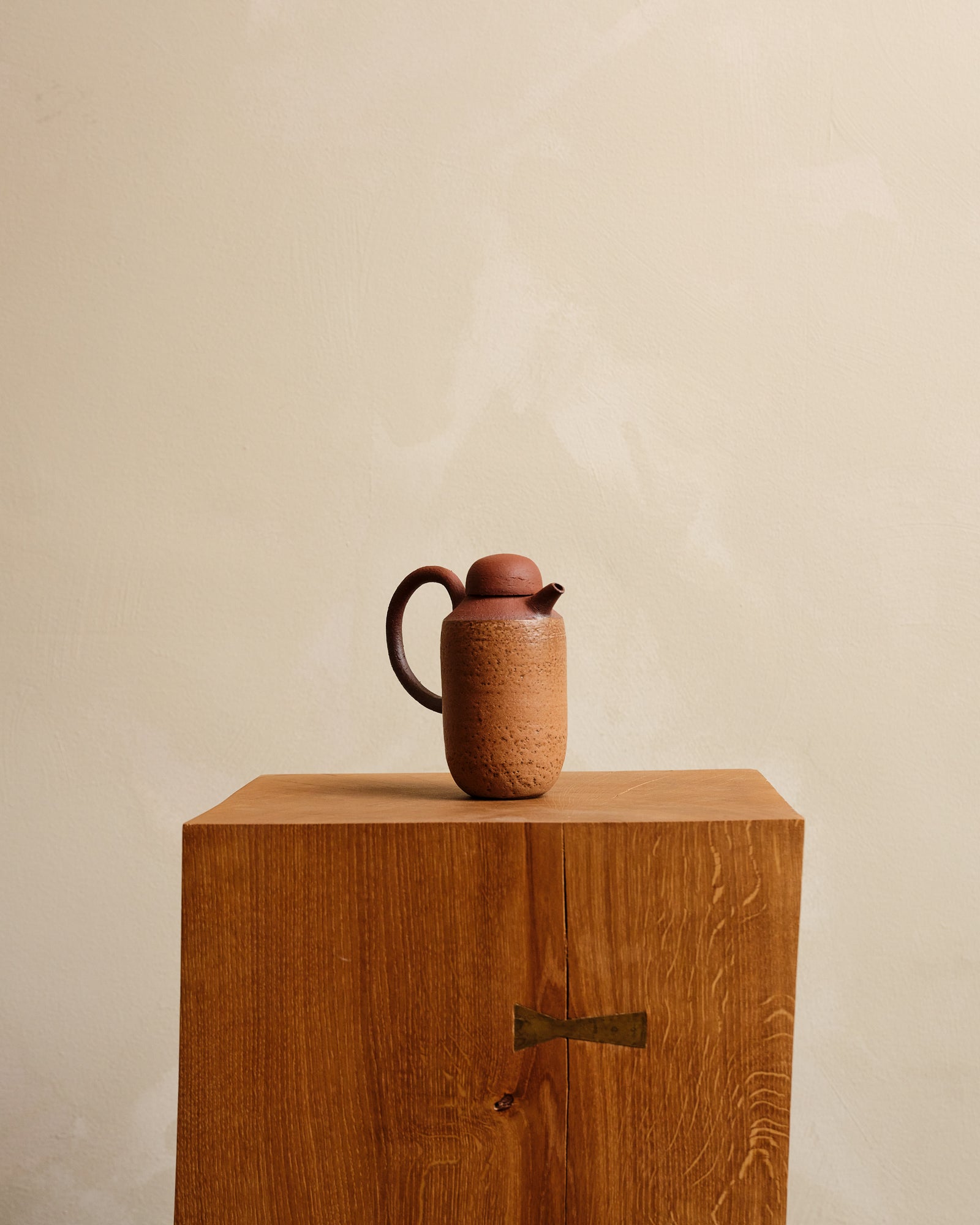 Ceramic bottle on a wooden stand against a beige background