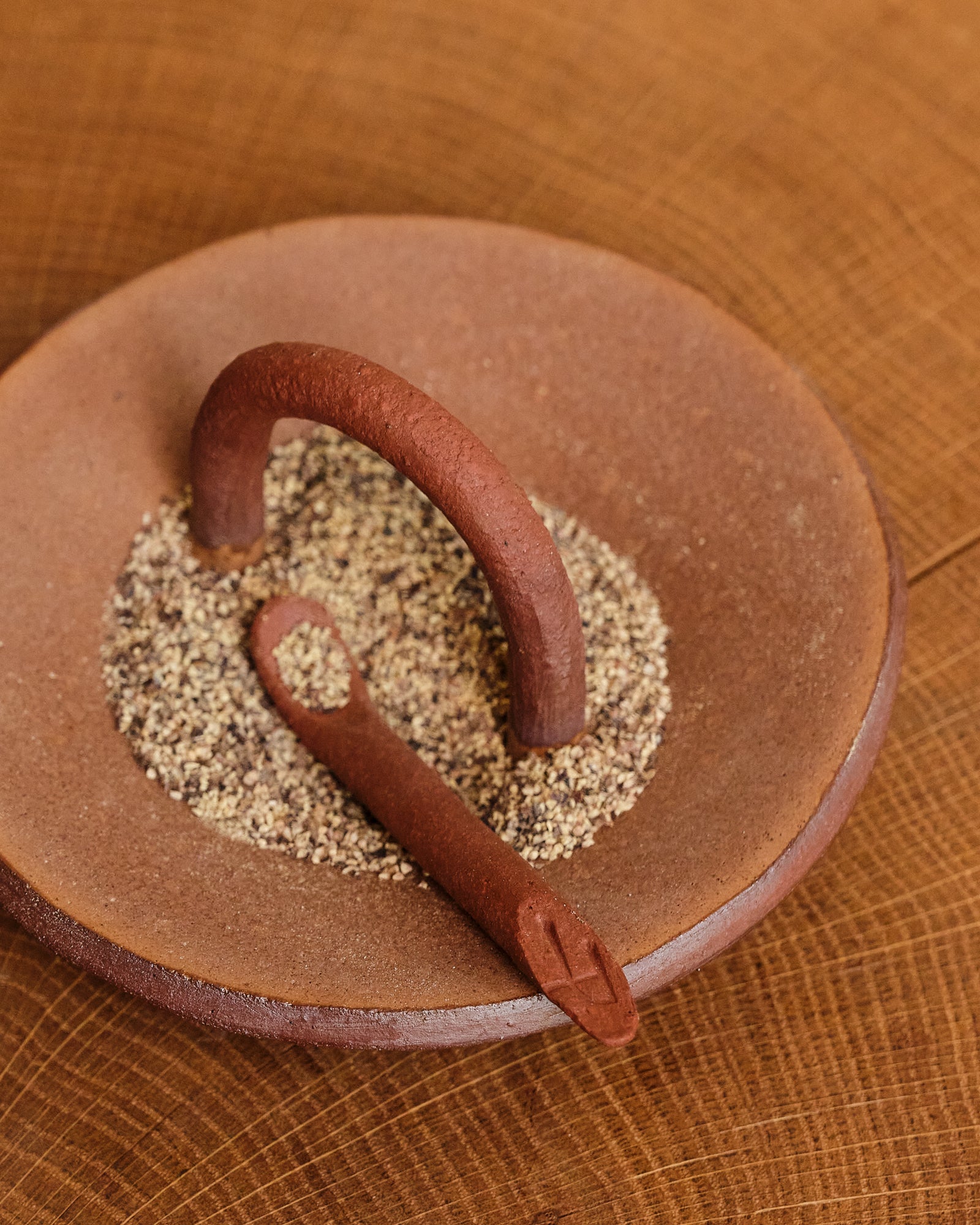 Ceramic spice pincher with spices on a wooden surface