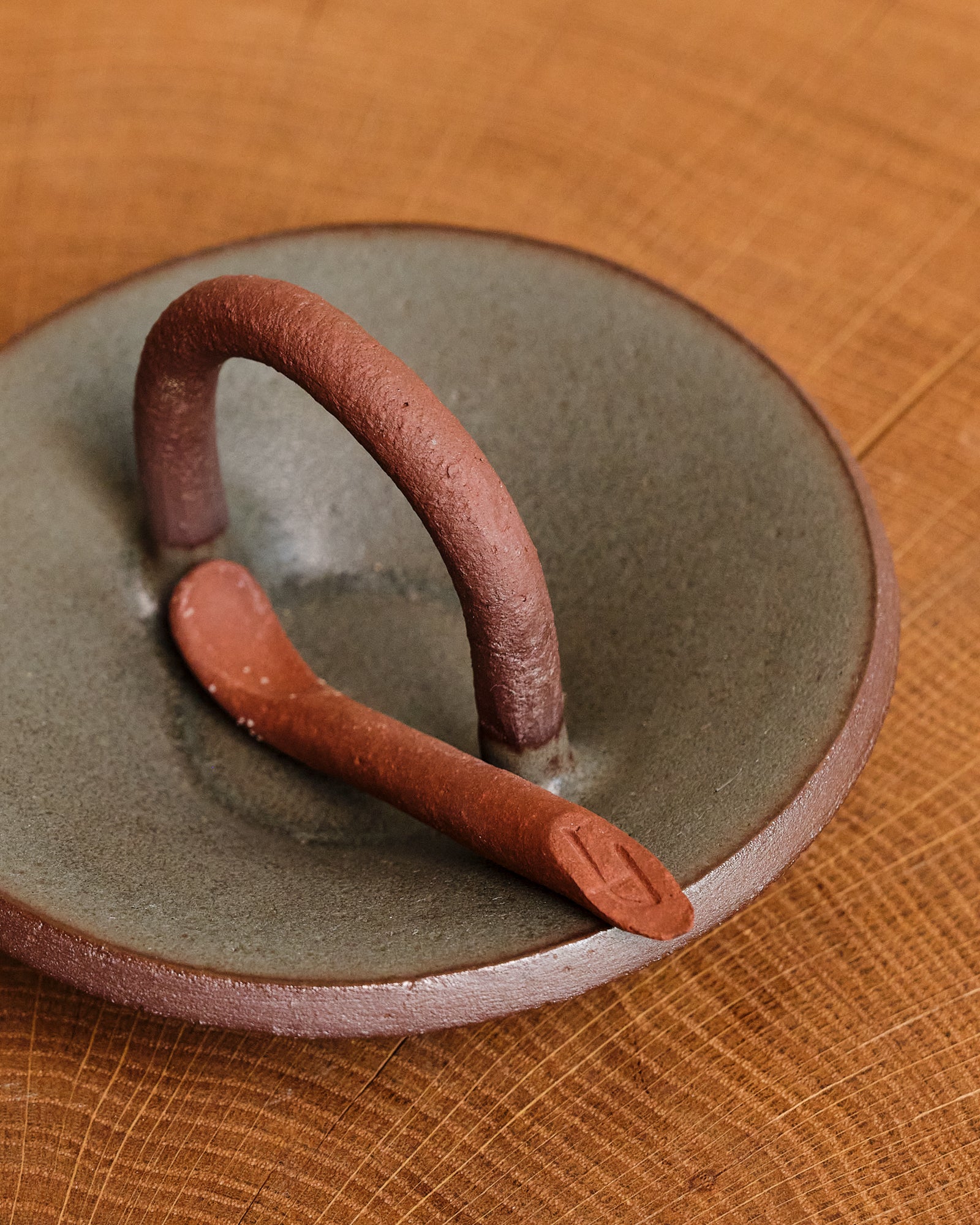 Ceramic spice pincher with a handle on a wooden surface
