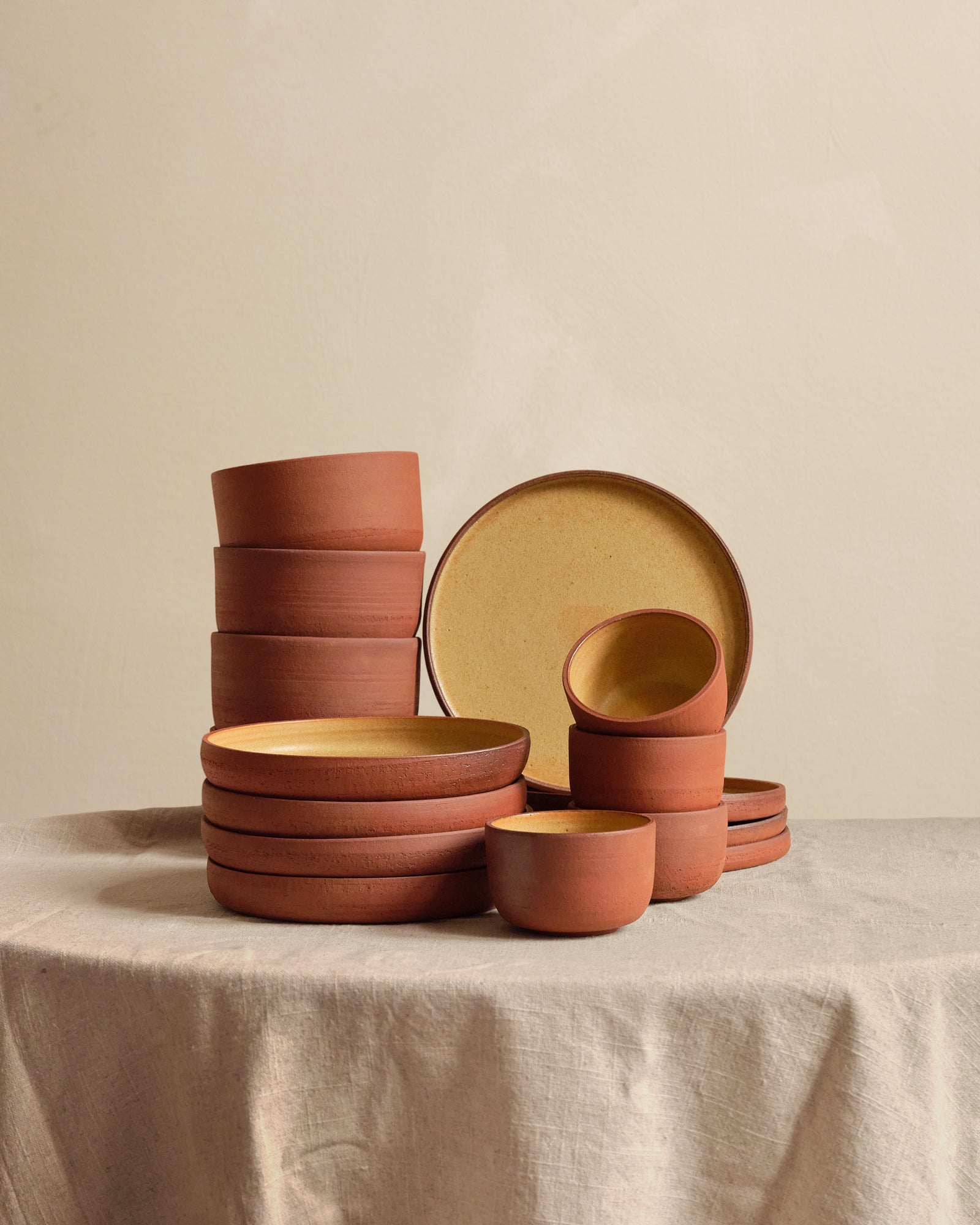 Set of terracotta bowls and plates on a beige surface with a neutral background