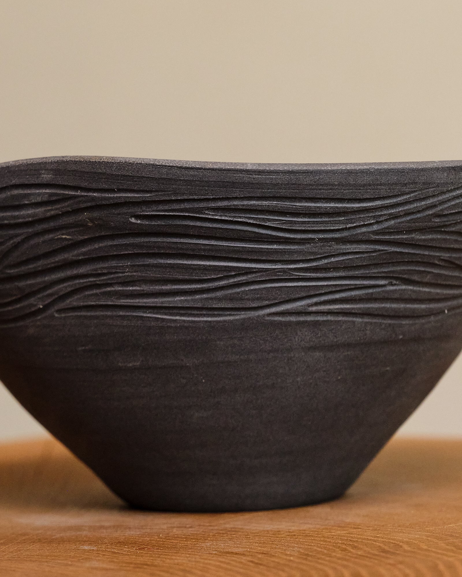 Black ceramic bowl with wavy texture on a wooden surface