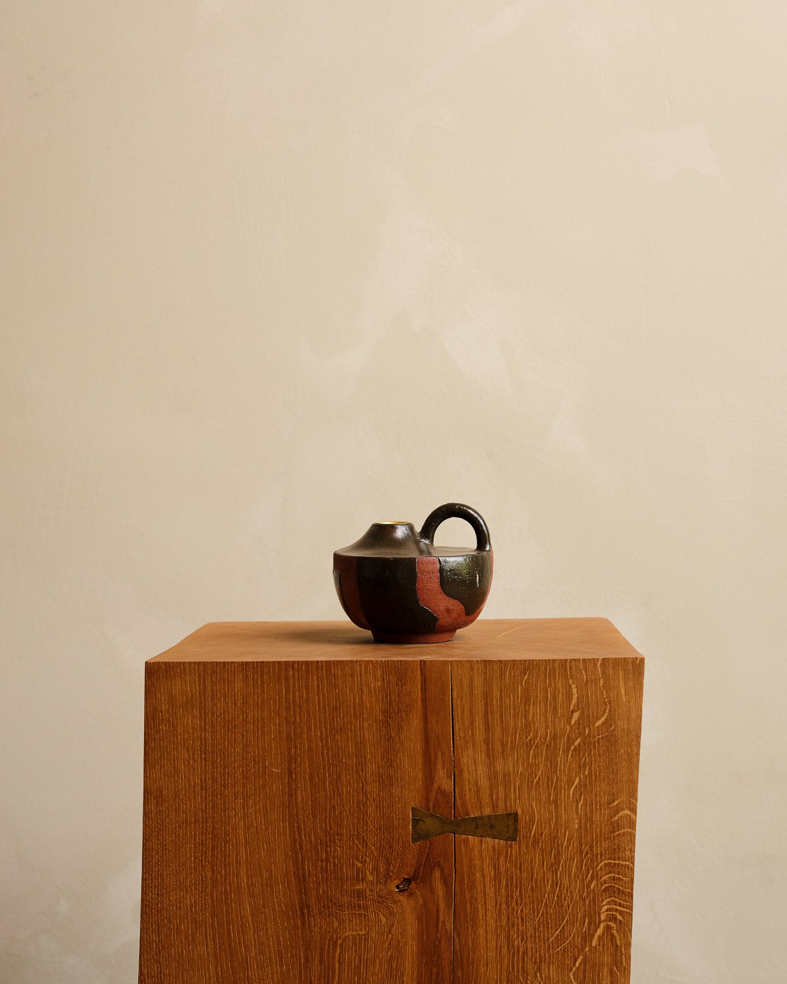 Ceramic vase with black pattern on a wooden pedestal against a beige background