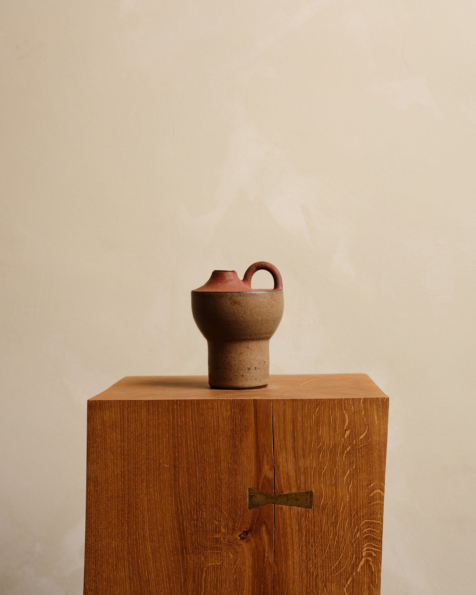 Ceramic vase on a wooden pedestal against a beige background
