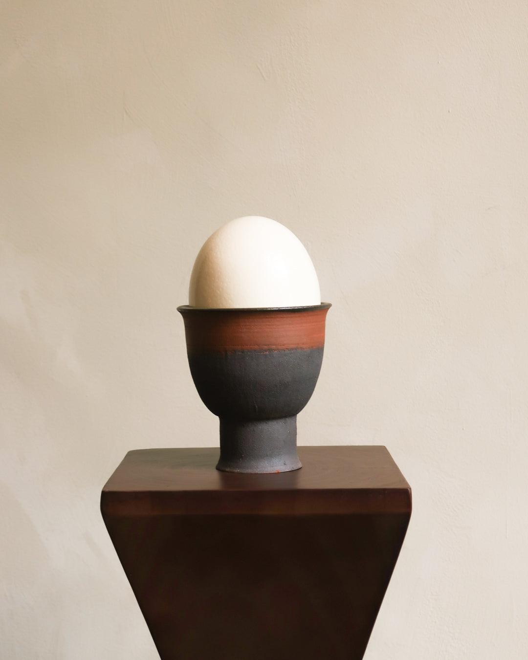 Ceramic egg cup with a white egg on a beige background