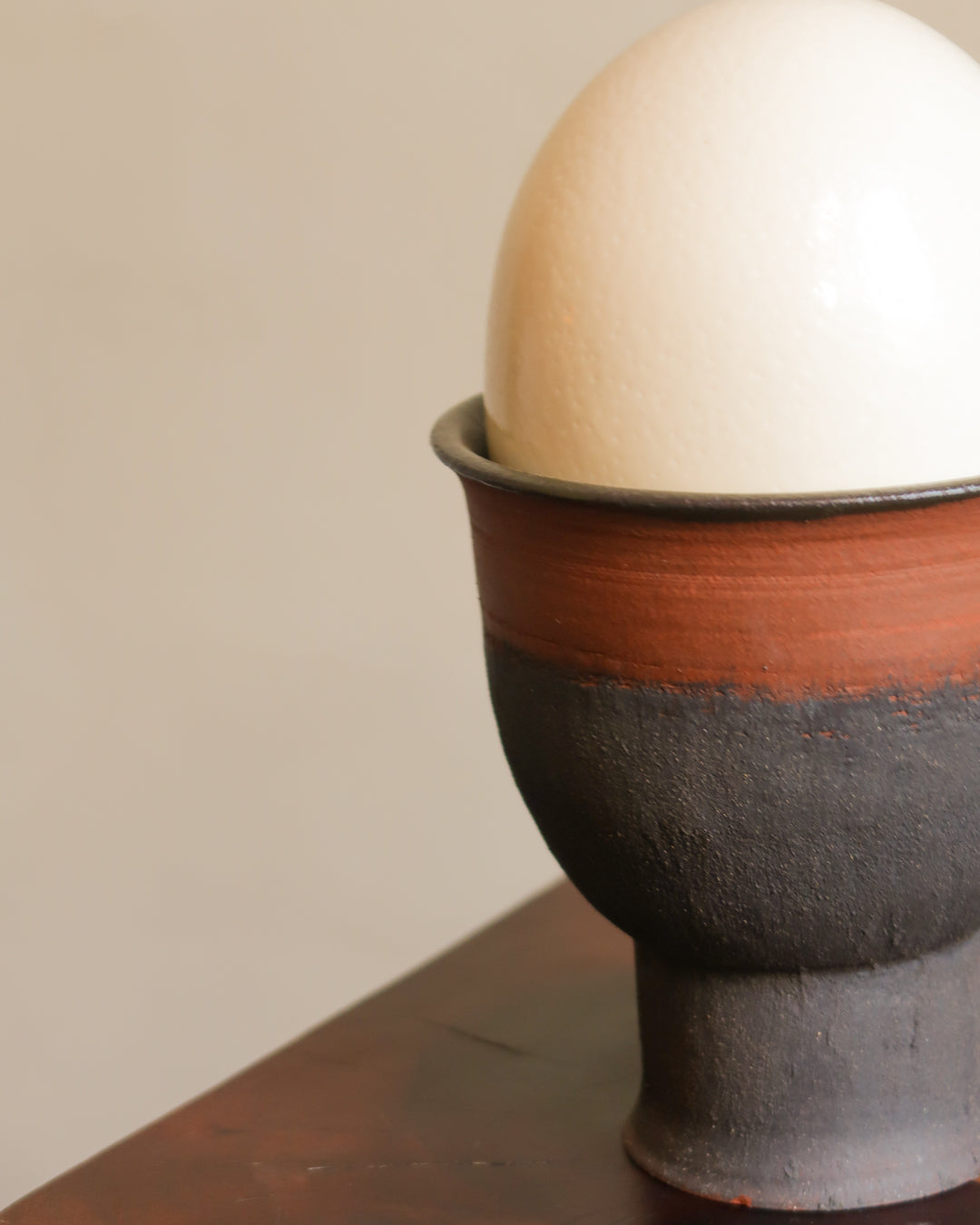 Ceramic egg cup with a white egg on a neutral background