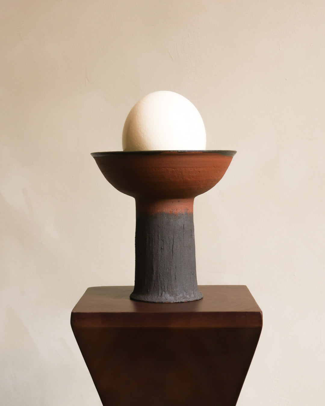 Ceramic sculpture with a bowl and egg on a beige background